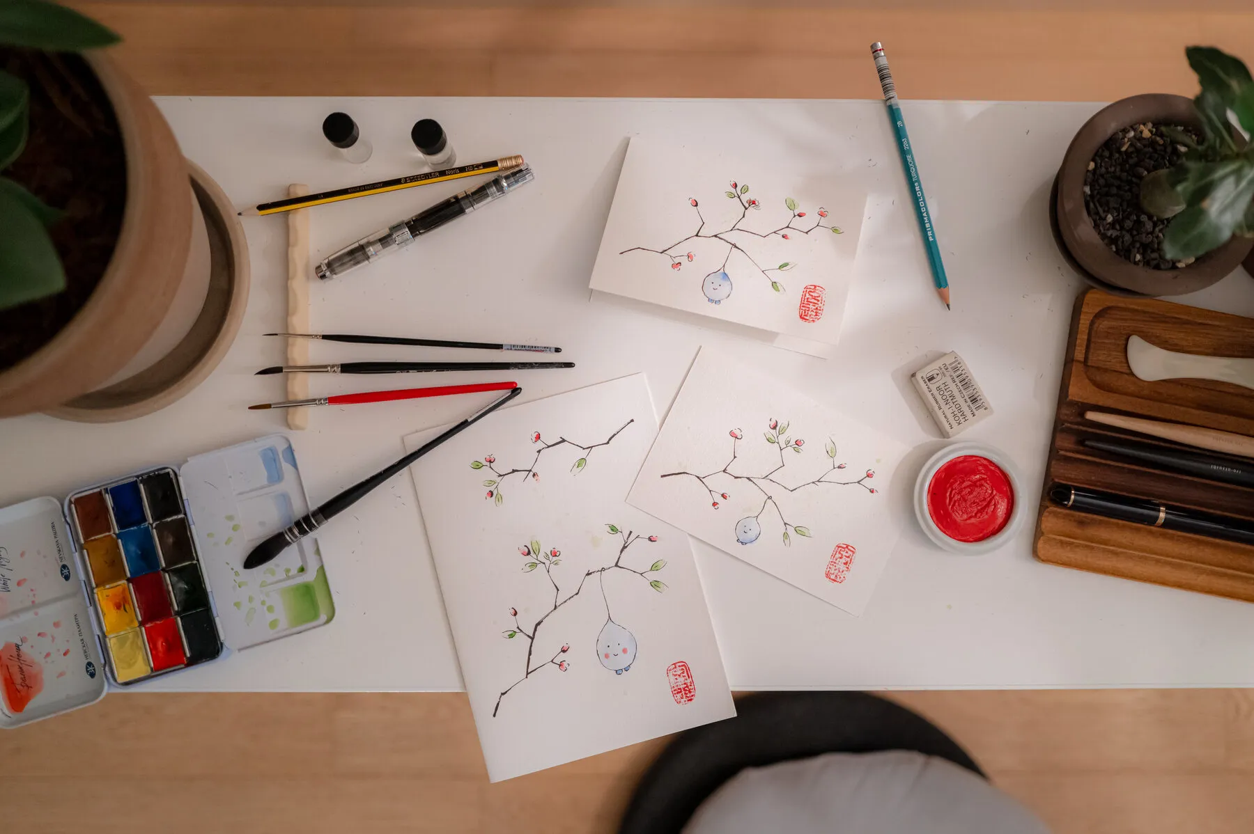 Painted notebook pieces, brushes and colour spread across the Studio Monjo worktable