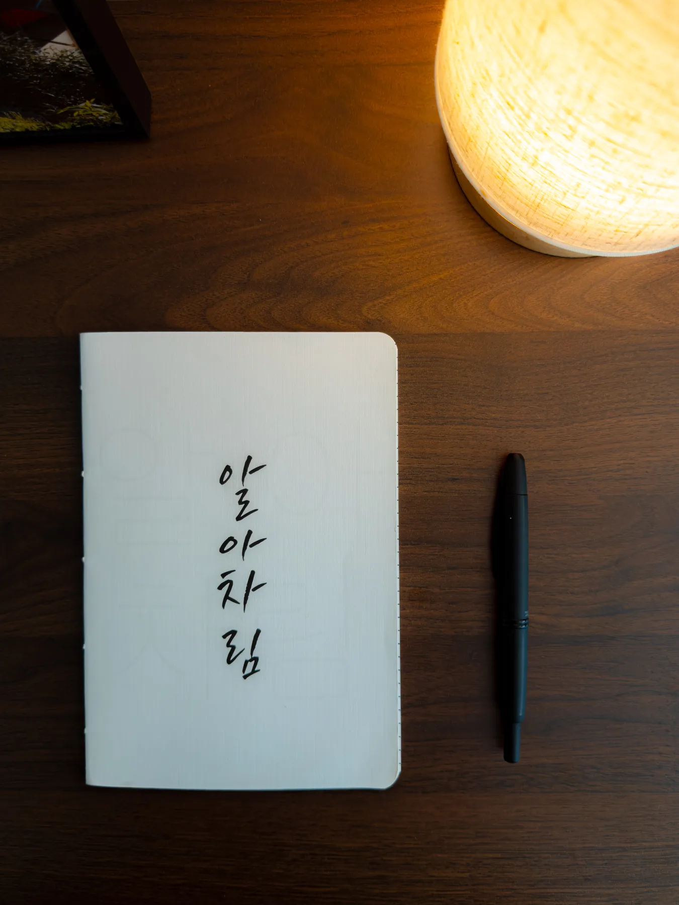 A long white hand-bound notebook with Korean calligraphy written down its cover