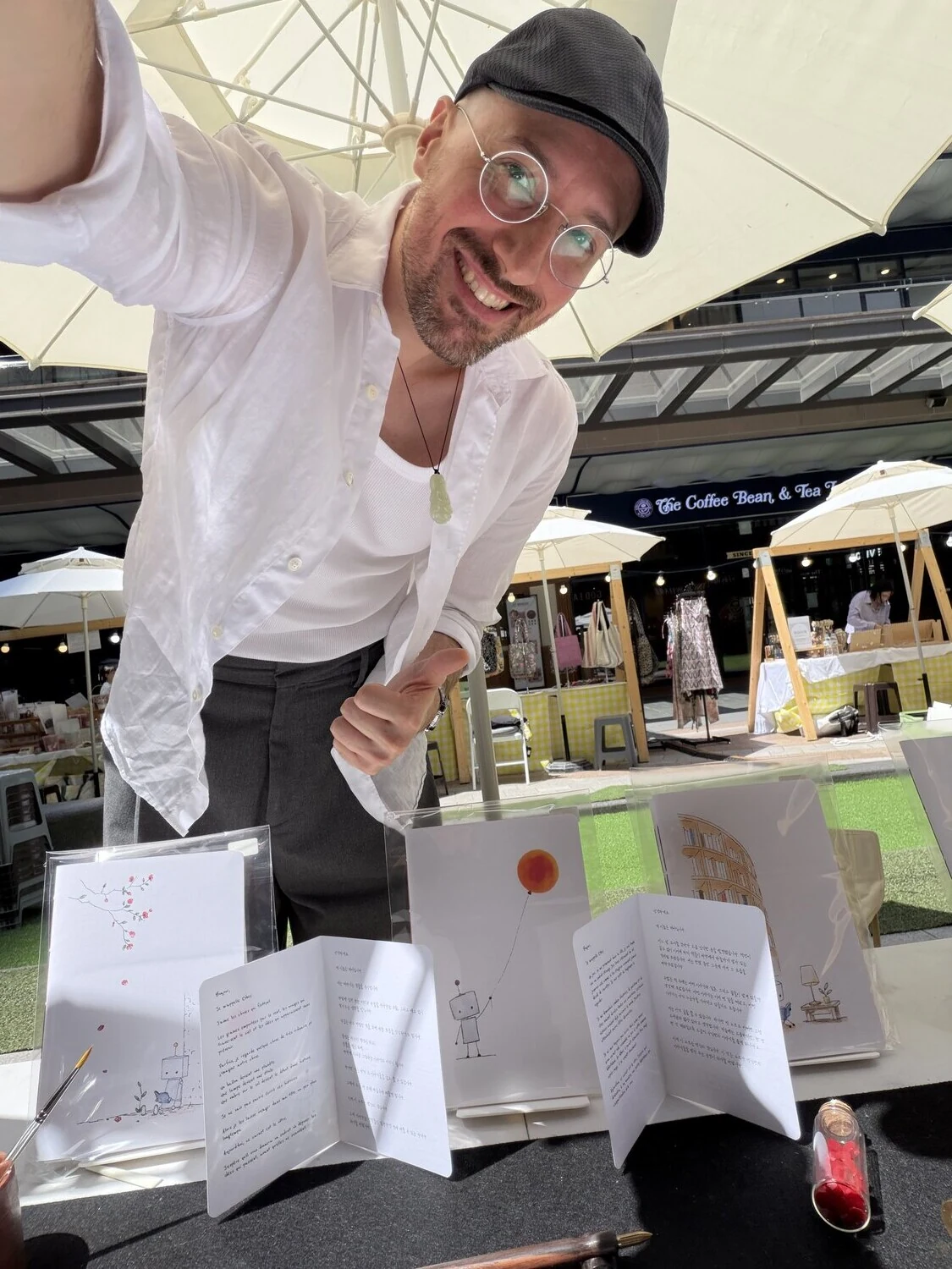 Jordan smiling at his market table, surrounded by the notebooks he makes